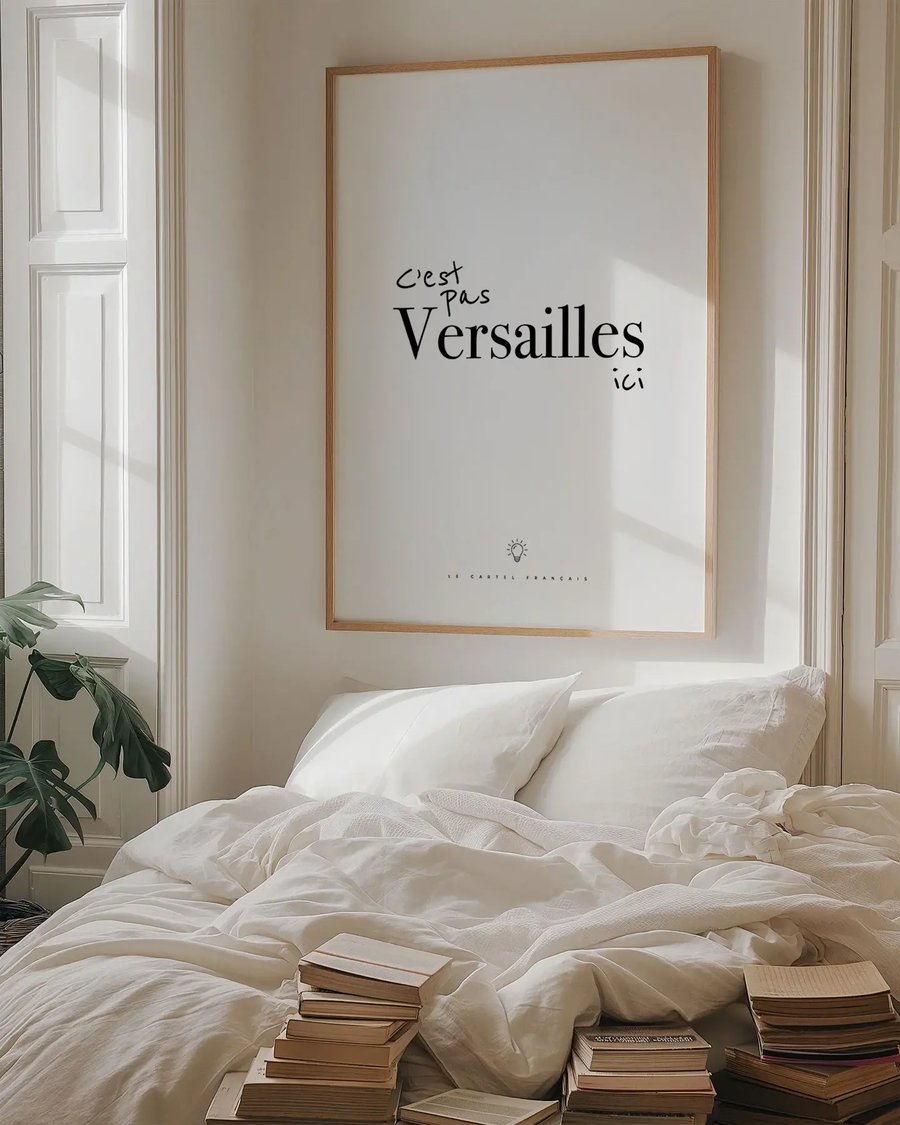 Affiche C’est pas Versailles ici encadrée au-dessus d’un lit