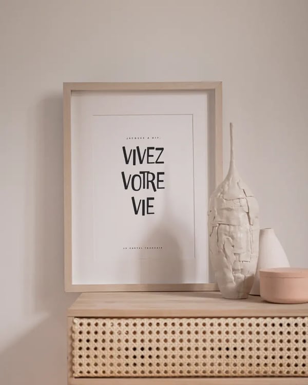 Affiche Jacques a dit, vivez votre vie, encadrée sur un meuble en cannage