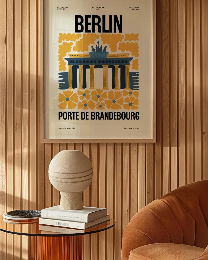 L’affiche Berlin encadrée sur un mur en lattes de bois, au-dessus d’une table d’appoint et d’un fauteuil orange