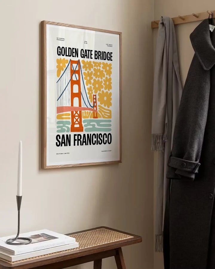 L’affiche Golden Gate Bridge accrochée au-dessus d’un banc d’entrée, à côté d’un long manteau noir