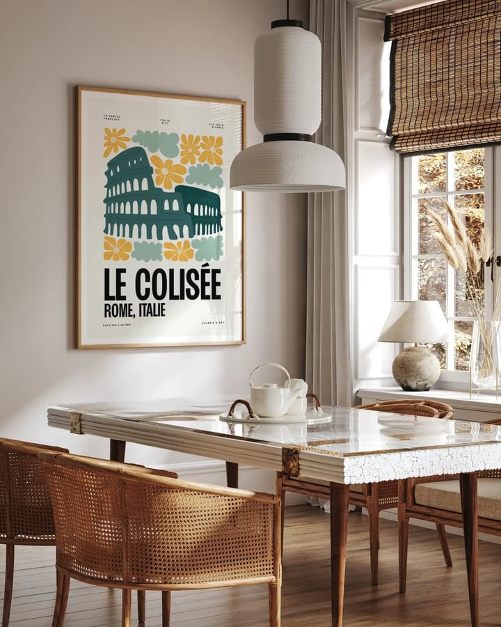 L’affiche du Colisée encadrée dans une salle à manger lumineuse, au-dessus d’une table et de chaises cannées