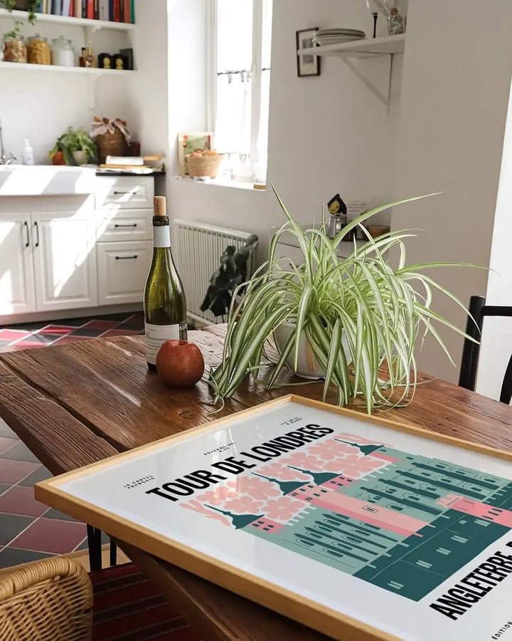 L’affiche Tour de Londres encadrée, posée sur une table de ferme près d’une plante verte, dans une cuisine blanche