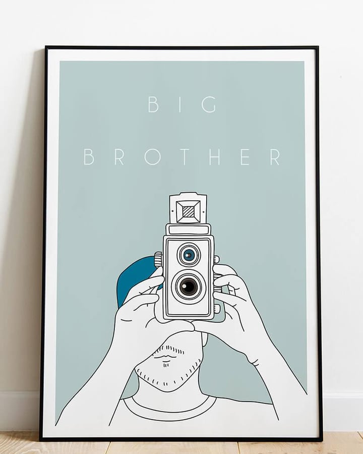 L’affiche Big Brother dans un cadre noir, posée sur un parquet clair contre un mur blanc