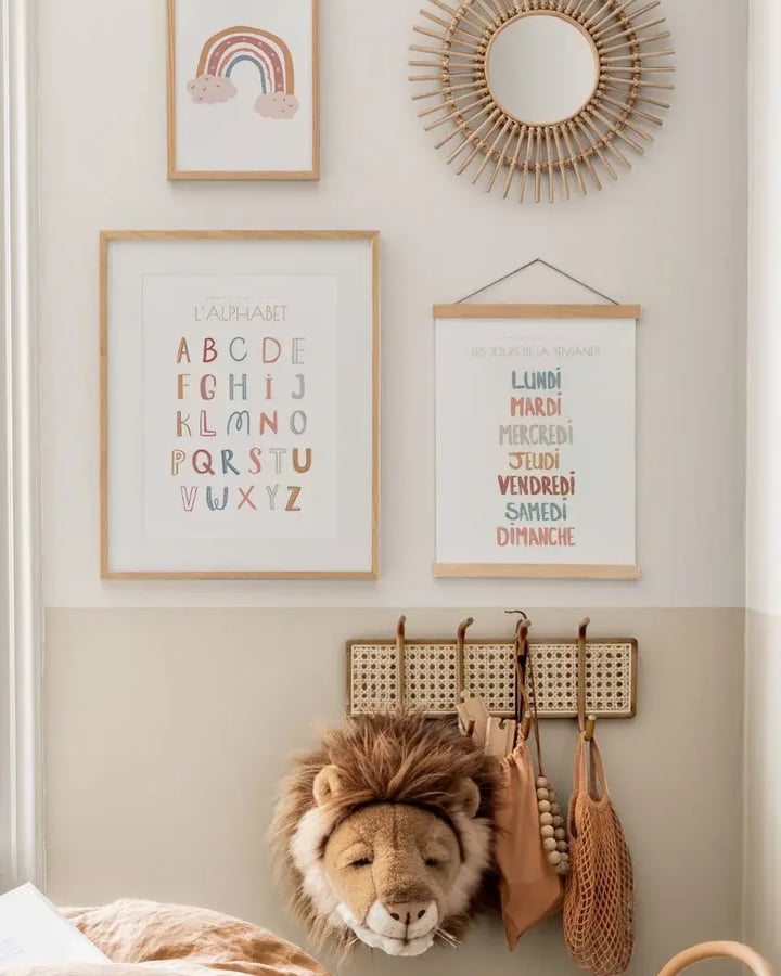 L’affiche Arc-en-ciel encadrée de bois clair près d’un miroir soleil en rotin, au-dessus de L’alphabet et des Jours de la semaine