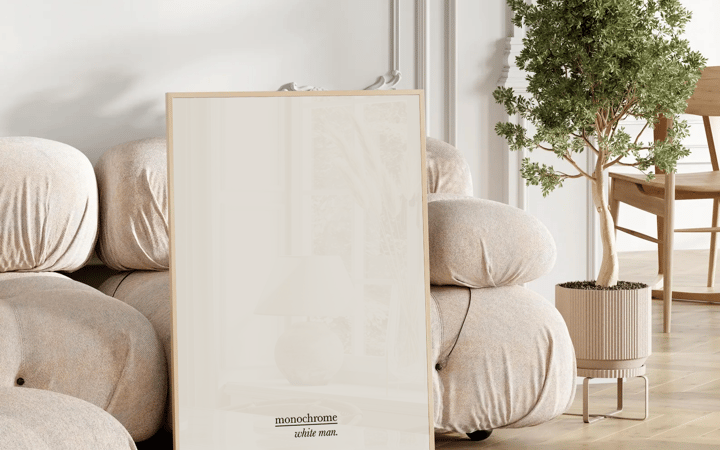 Affiche Monochrome de Whiteman posée au sol dans un salon clair, à côté d’un canapé bouclette